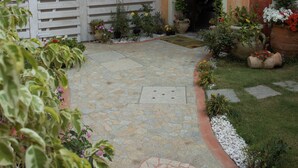A courtyard with a stone pathway, potted plants, and a wooden fence.