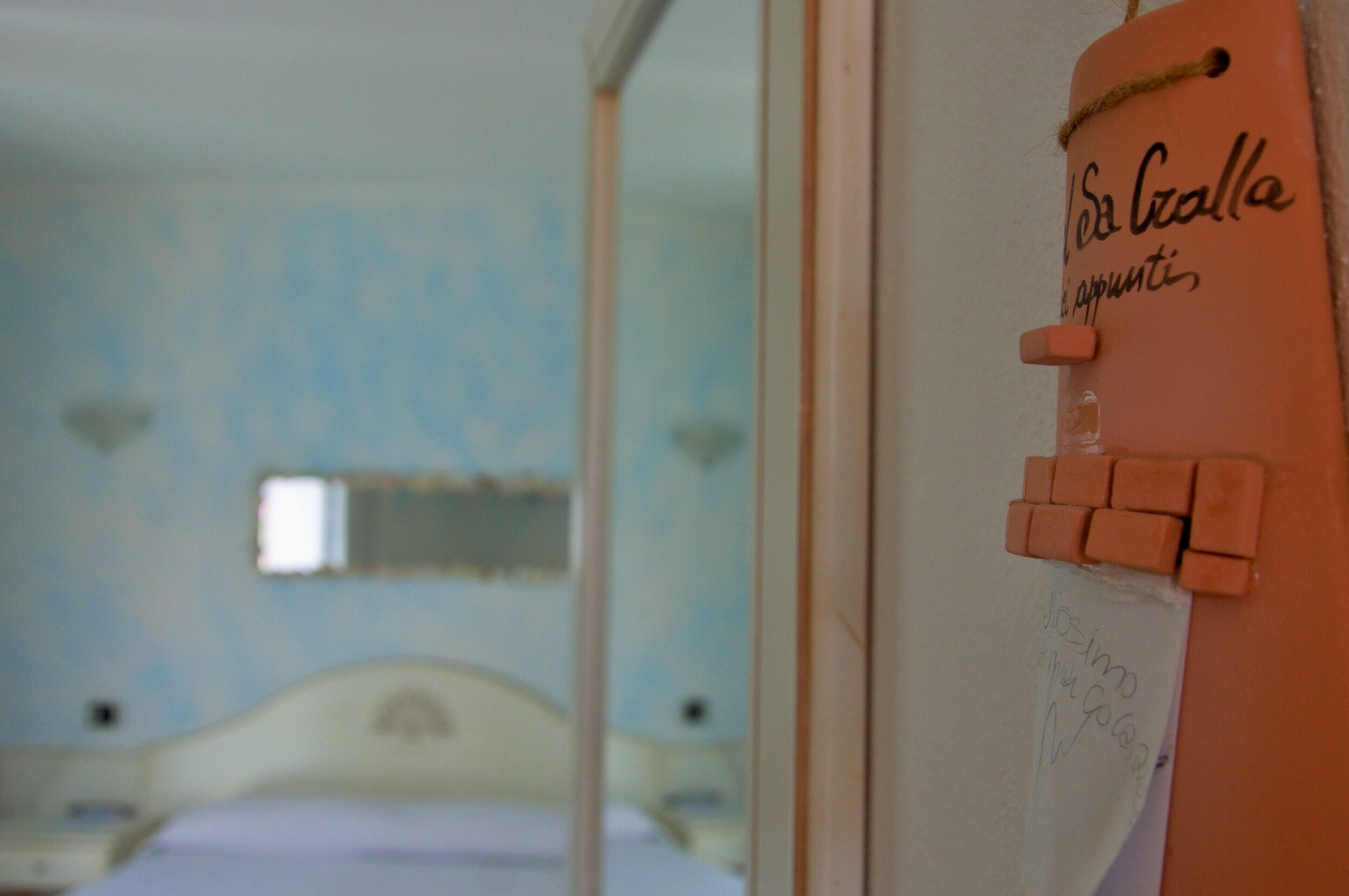 A bedroom with a bed, a window, and a door with a sign.