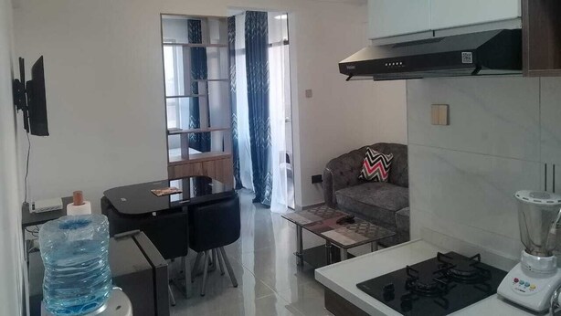 Een moderne keuken met een kookplaat, een blender en een eethoek met een tafel en stoelen.