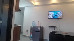 Een moderne keuken met een koelkast, waterdispenser en een flatscreen televisie aan de muur.