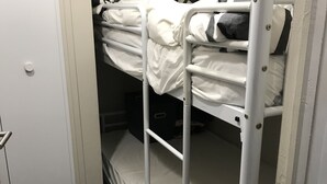 A bunk bed in a narrow room with a door on one side and a white wall on the other. - Studio Agréable Près de Toutes Commodité (Berck)