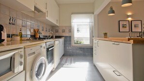 Cocina compacta con lavadora, estufa y ventana que proporciona luz natural.