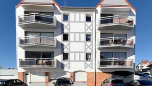Ein mehrgeschossiges Wohnhaus mit Balkonen, einer Garage und geparkten Autos.