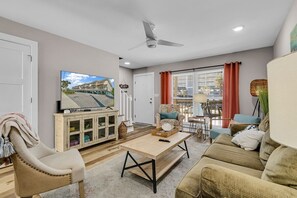 A living room with a TV, sofa, armchair, and a coffee table.