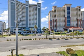 A multi-story hotel with a central courtyard, a parking lot, and a street view.