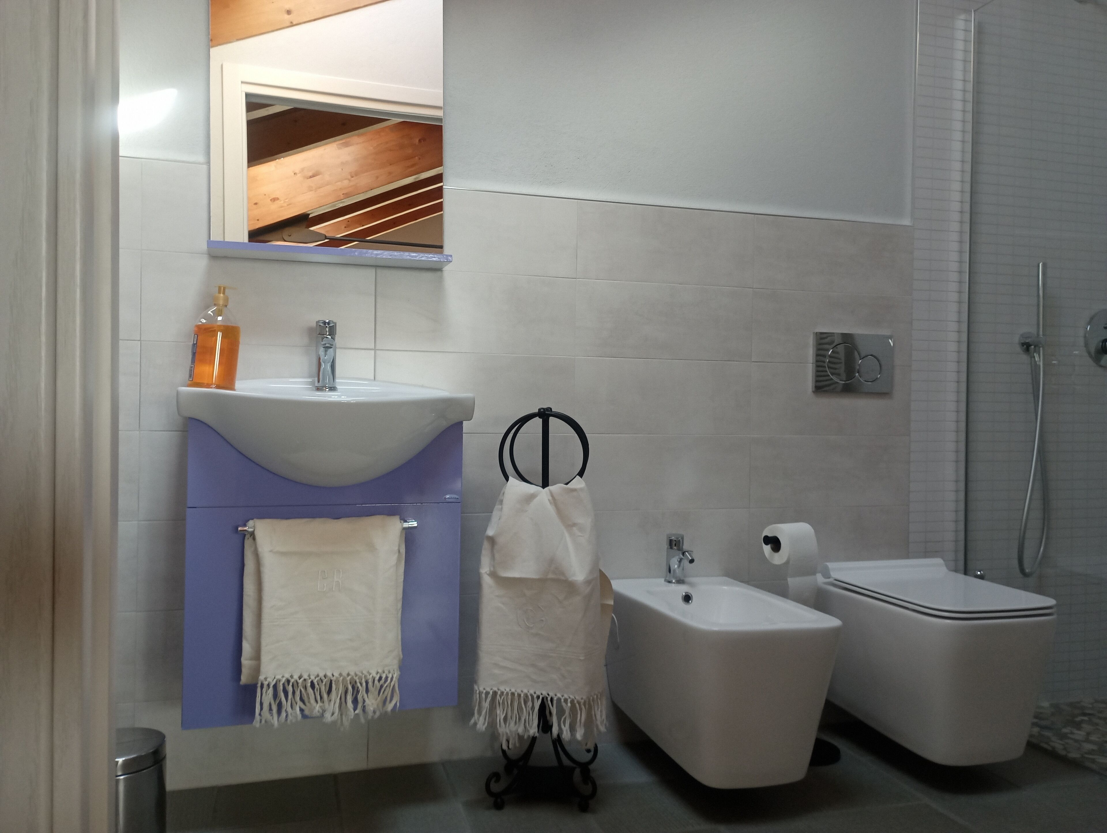 A modern bathroom with a sink, bidet, and shower.