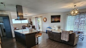 En rummelig opholdsstue med en central ø, sofa og spisebord.