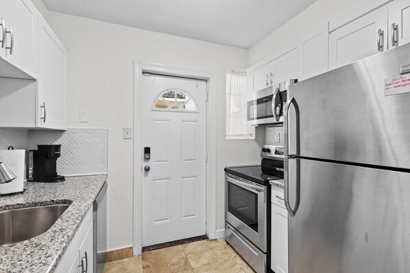 A modern kitchen with white cabinets, stainless steel appliances, a built-in oven, and a microwave.