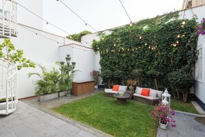 A courtyard with a grassy lawn, outdoor seating, and a wall covered in greenery. - Casa Cáceres (Lima)