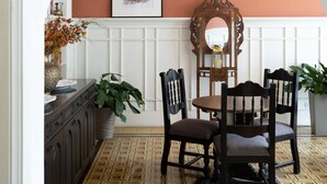 A dining area with a table and chairs, a mirror, and a potted plant.