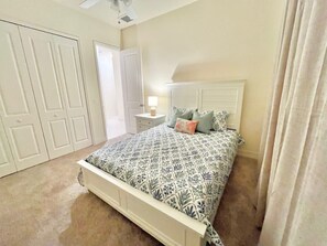 A bedroom with a bed, nightstand, and a door.