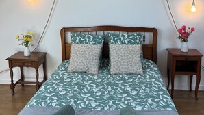 Une chambre à coucher avec un lit en bois, deux tables de chevet avec des lampes, un tableau encadré au mur et une fenêtre donnant sur un paysage.