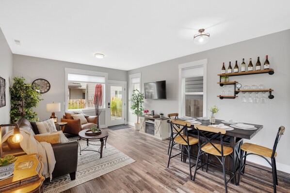 A modern living room with a sofa, coffee table, and dining area with chairs and a table.