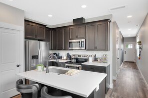 A modern kitchen with dark cabinets, stainless steel appliances, and a white countertop.