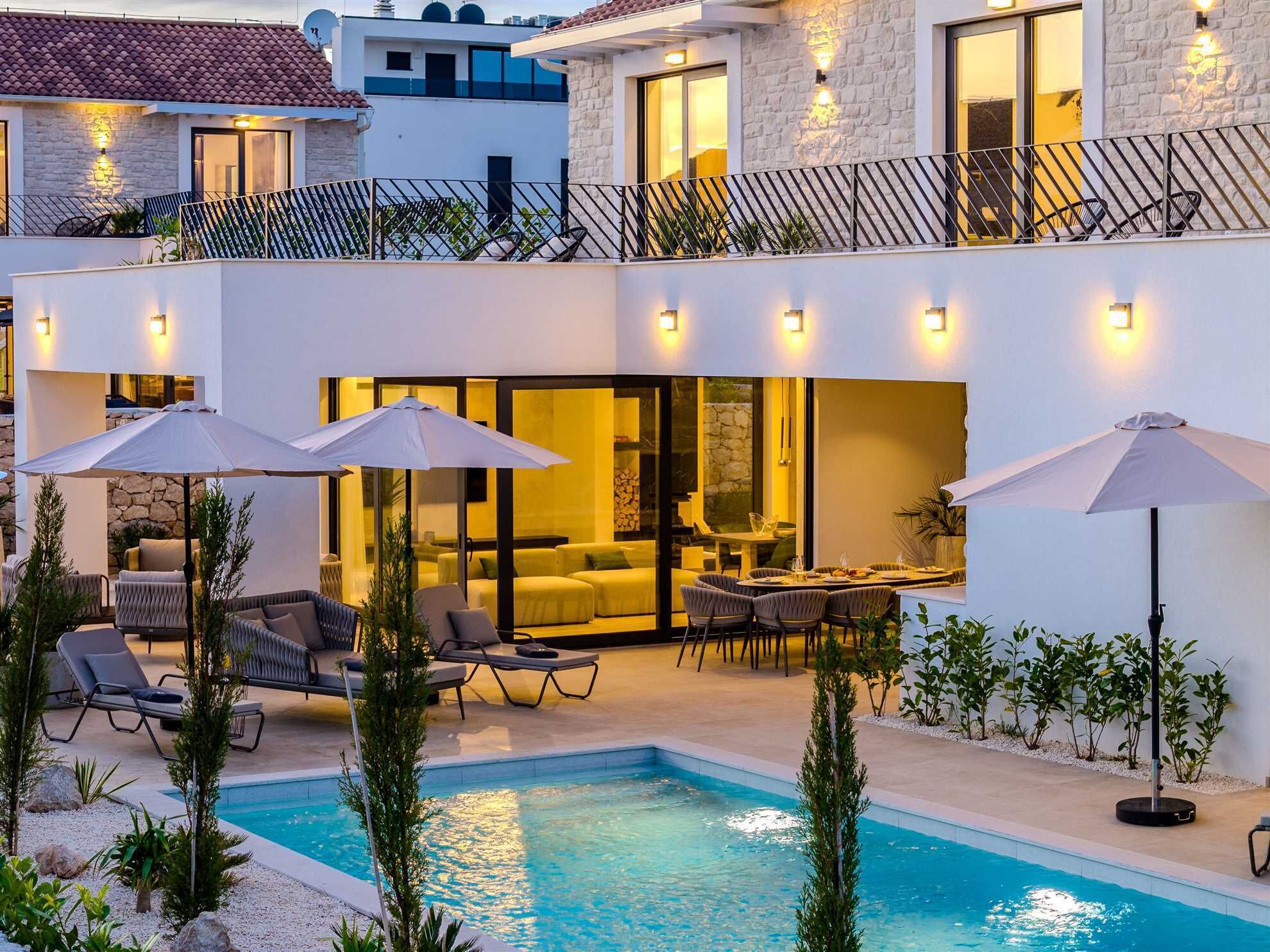 A modern two-story house with a swimming pool, outdoor seating, and a dining area.