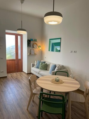 A dining area with a round table, green chairs, and pendant lighting. - Relaxing villa with terrace and garden - Procida center - Quartiere Chiaiolella (Procida)