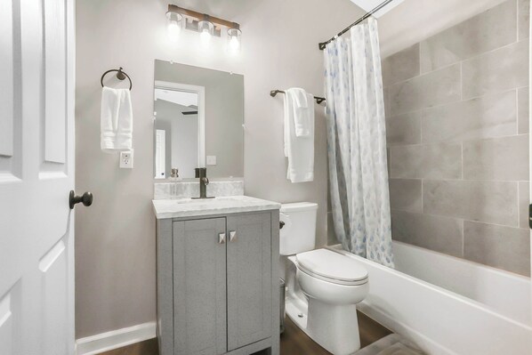 Un baño con inodoro, lavabo, espejo y cortina de ducha.