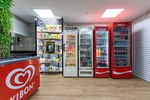 A vending area with a Kibon counter, a refrigerated display, and two Coca-Cola vending machines.