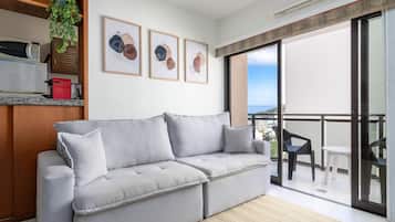 Una sala moderna con un sofá gris, una mesita y un balcón con vistas.
