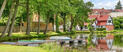 A riverside view with a dock, trees, and traditional houses with red roofs.
