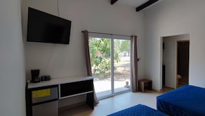 Ein Zimmer mit einem Bett, einem Schreibtisch mit Fernseher und einem Fenster mit Vorhängen.