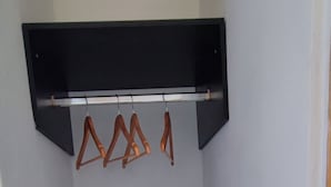 Ein Eckzimmer mit einer hölzernen Bank, einem schwarzen Regal und drei Holzaufhängern.