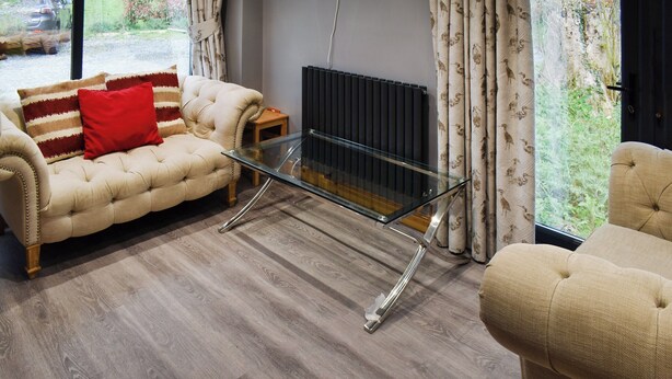 A living room with a sofa, armchair, and glass coffee table. - 6 bedroom accommodation in Dover (Dover)