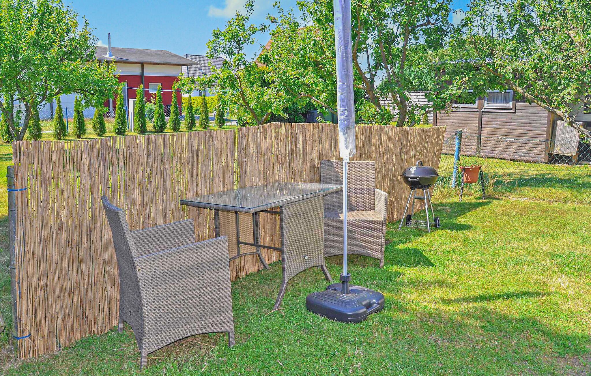 Un espacio al aire libre con mobiliario de mimbre, una mesa y una parrilla.