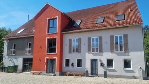 A two-story building with a red and white facade, multiple windows, and a cobblestone courtyard.