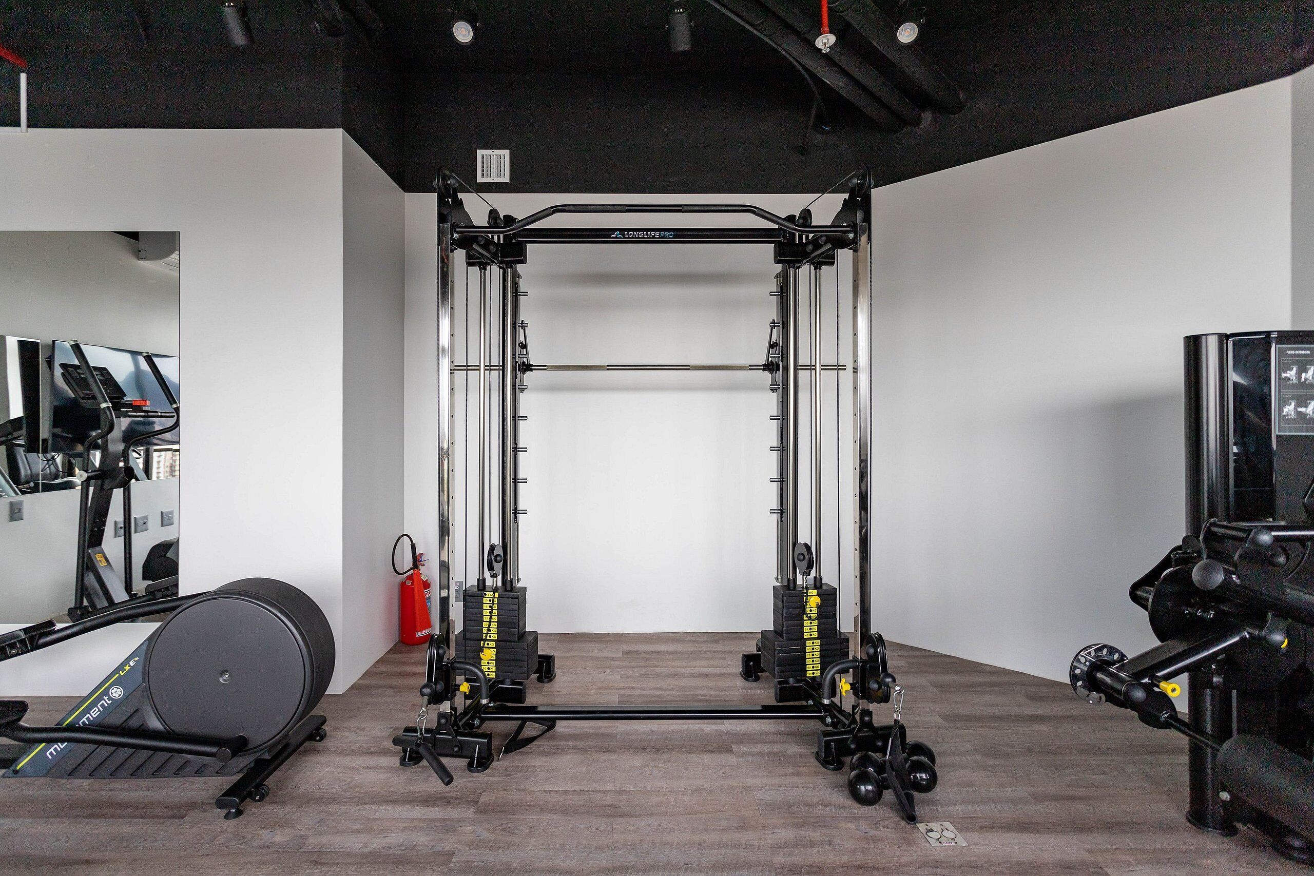 Une salle de sport équipée d’une barre de traction, d’un banc de musculation et d’autres appareils d’exercice.