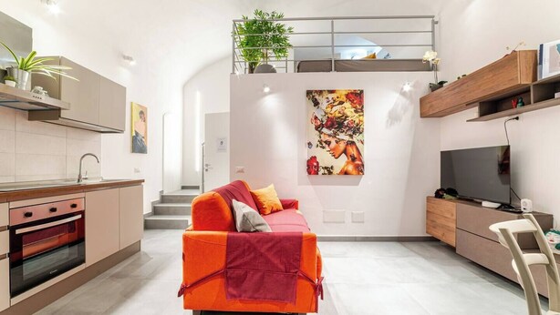Un espace de vie moderne comprenant une cuisine, un canapé, un téléviseur et un escalier.