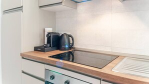 Une cuisine moderne équipée d’une plaque de cuisson à induction intégrée, d’une machine à café et d’une bouilloire posées sur le plan de travail.
