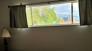 Une pièce avec un lit, une lampe et une fenêtre avec des rideaux.