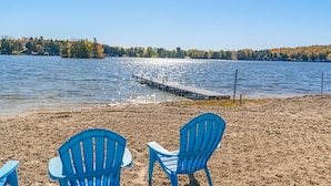 Ein Strand mit blauen Stühlen und einem Steg, der in einen See führt.