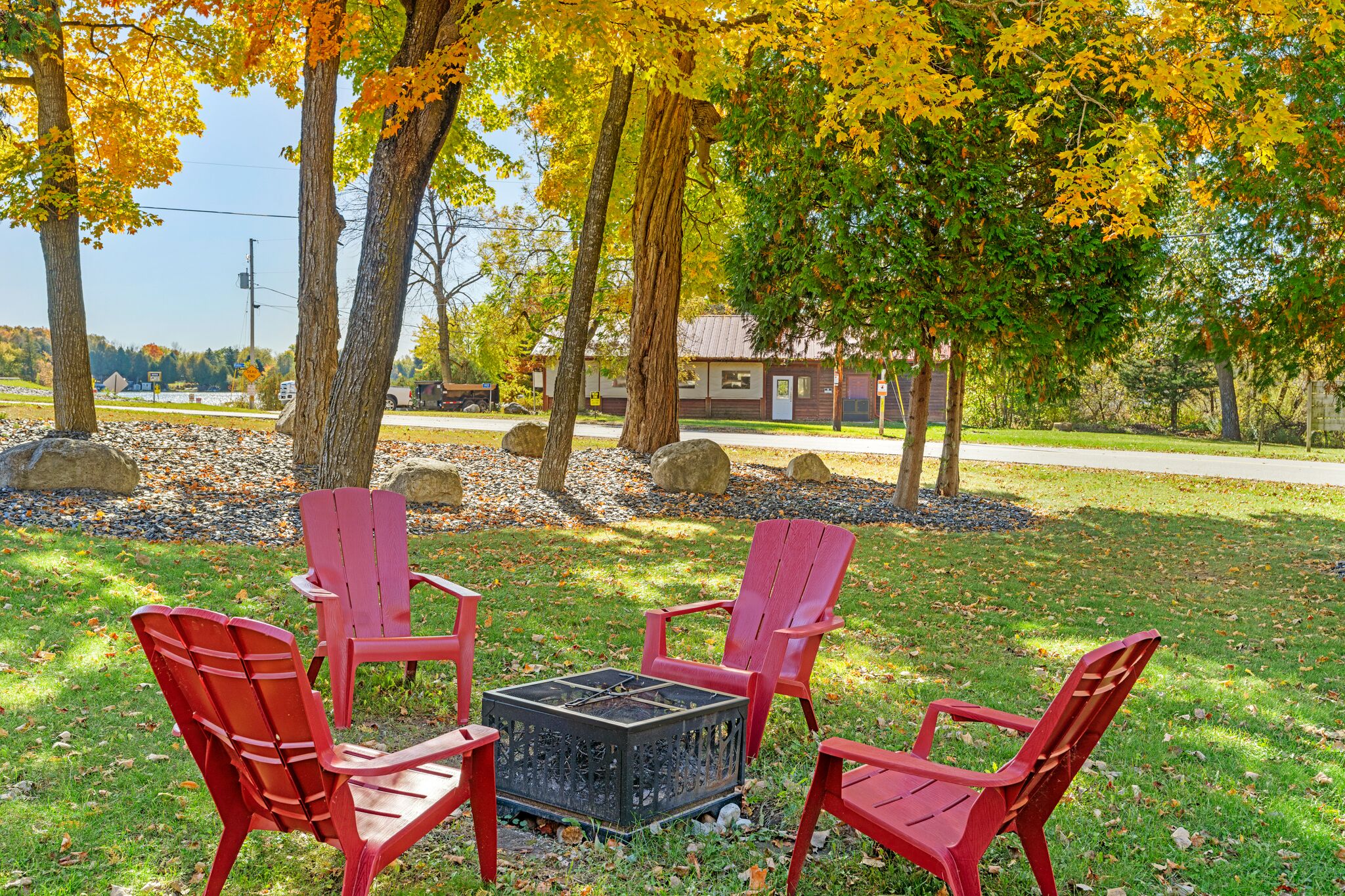 A patio area with four red Adirondack chairs and a square fire pit.