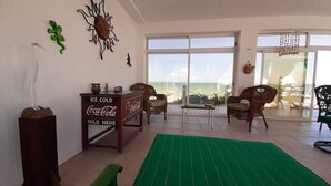 A room with a large window, a green mat, and a Coca-Cola refrigerator.