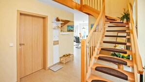 Un escalier en bois avec une rampe, une porte et un petit banc orné de citrons.