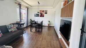 A modern living room with a sofa, dining table, and TV.