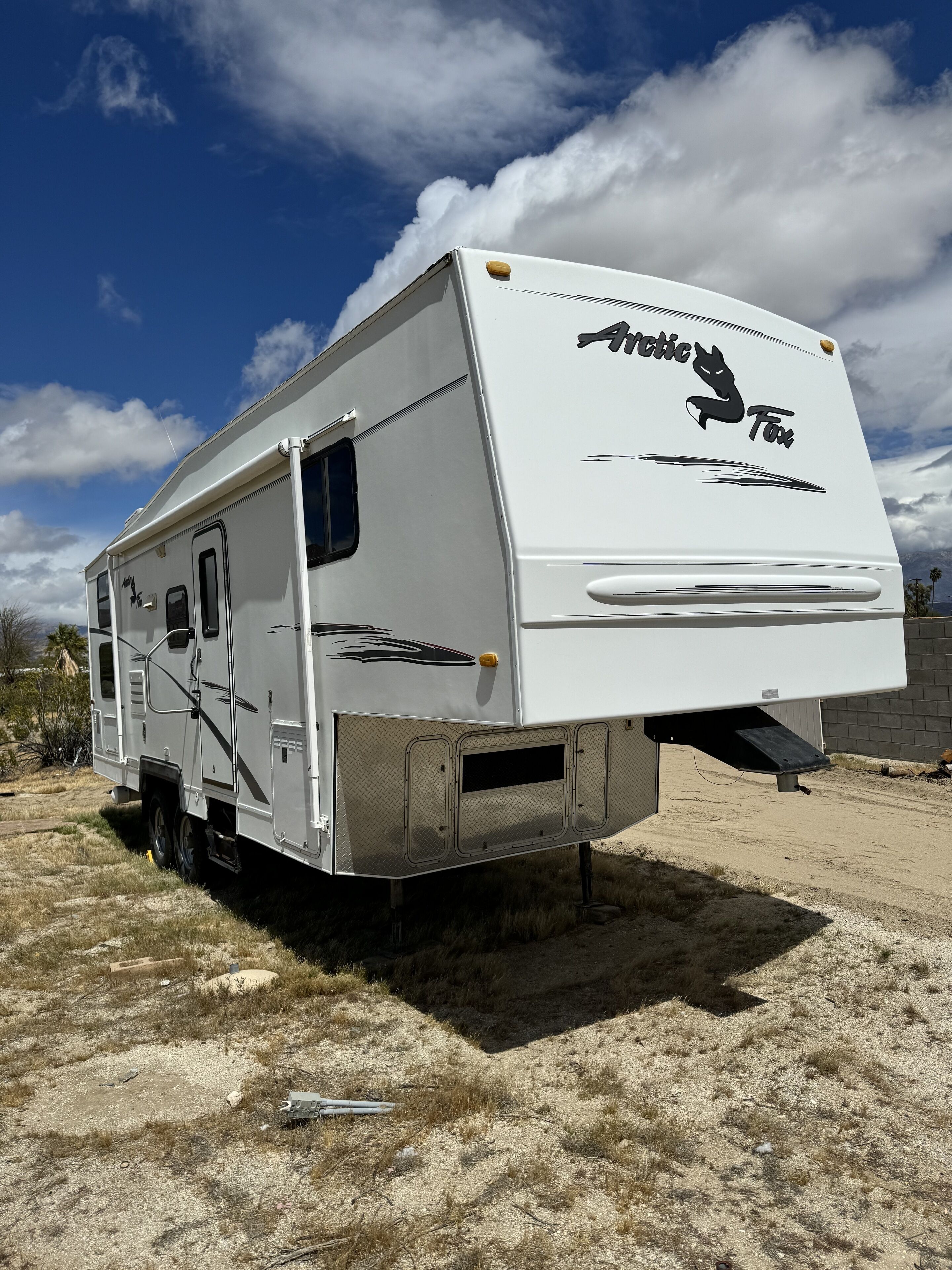 Una caravana blanca con el logo "Arctic Fox", una puerta corredera y una ventana pequeña.