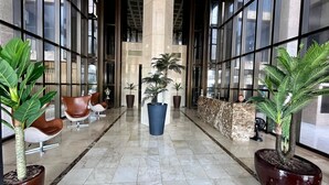 Un hall d’entrée avec un comptoir de réception, un espace salon et des plantes en pot.