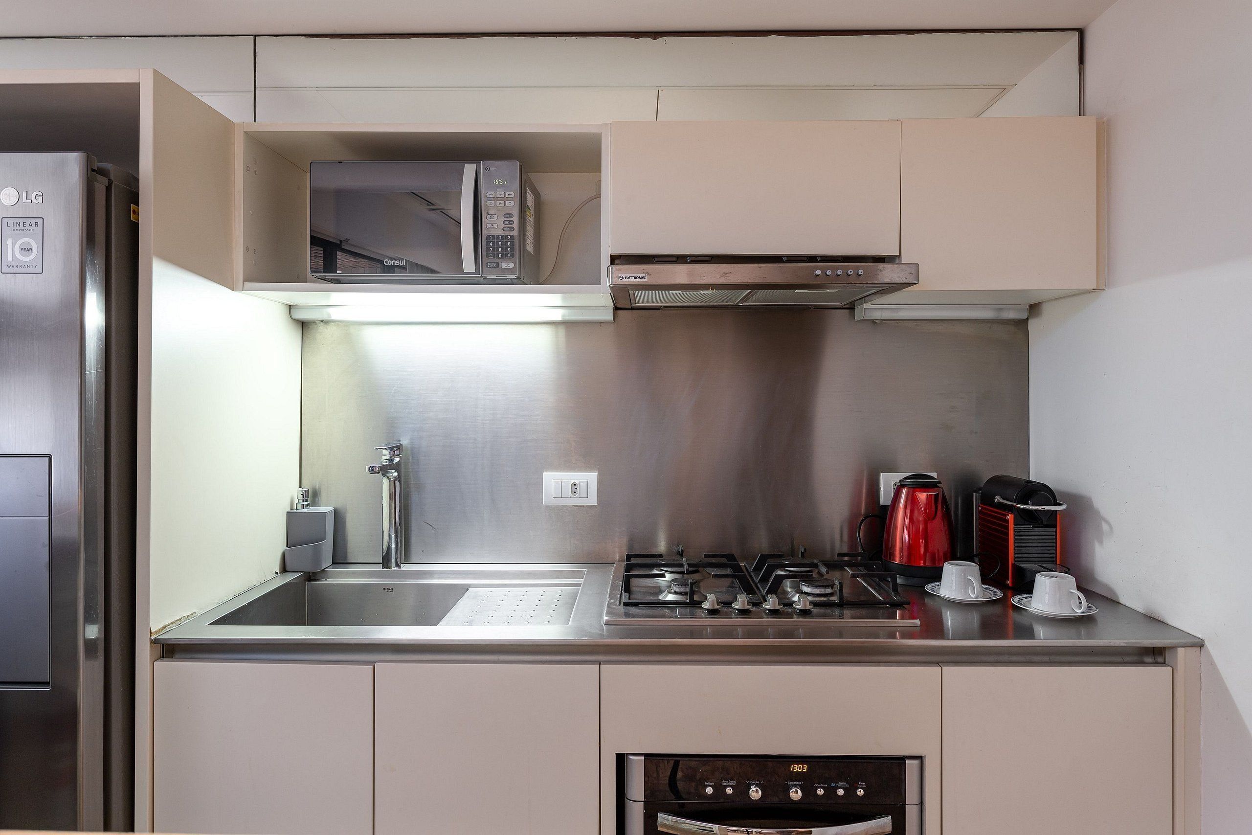 A compact kitchenette with a microwave, stove, and coffee maker.