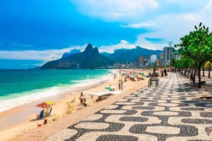A beach with a patterned walkway, a mountain in the background, and a cityscape. - 304 (Rio de Janeiro)