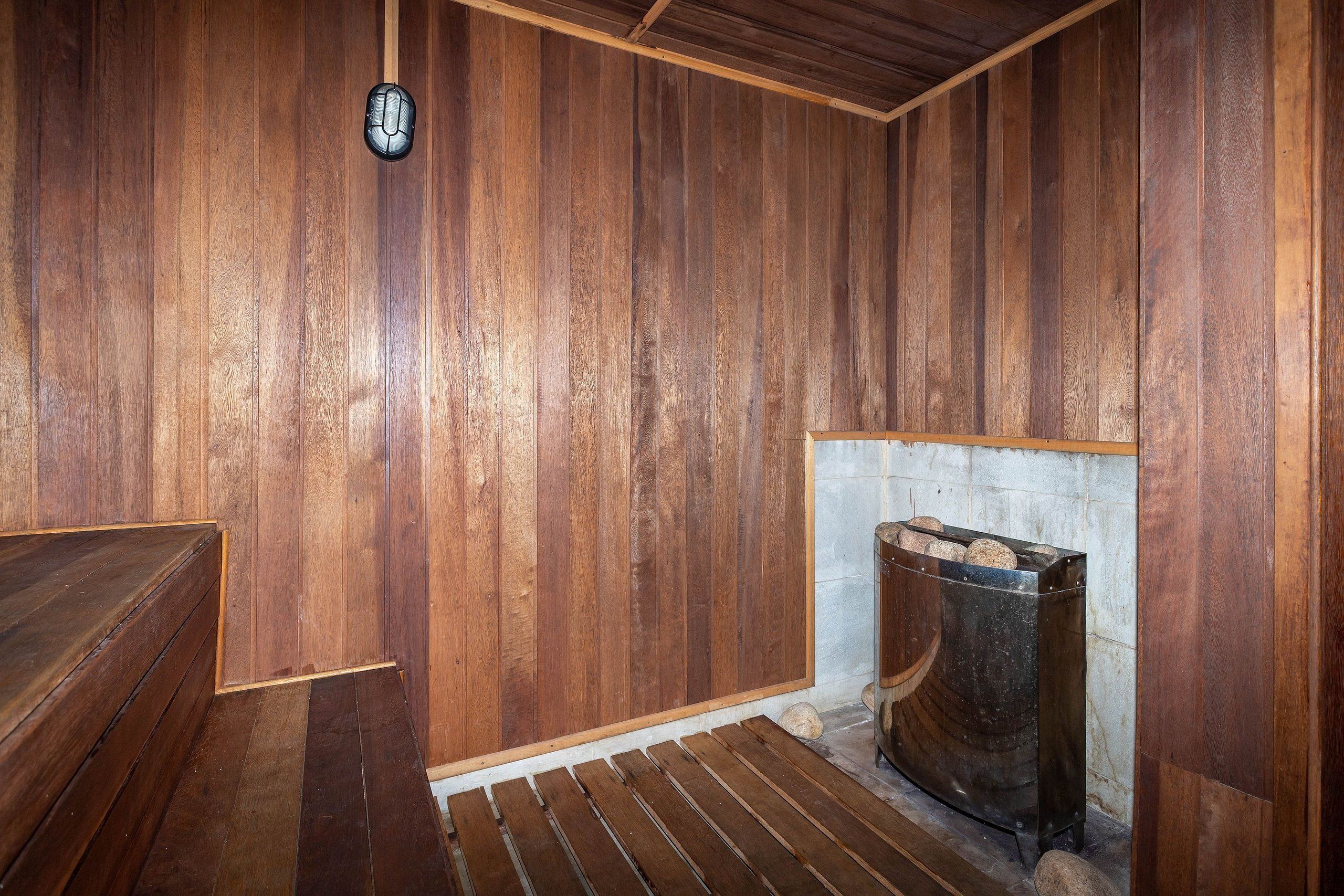 A wooden interior with a bench, a fireplace, and a clock on the wall.