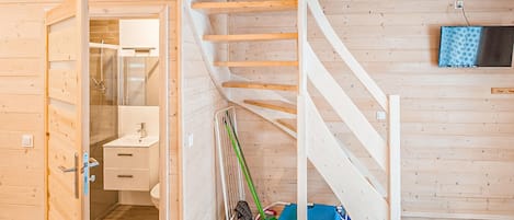 A wooden interior with a bathroom, a staircase, and cleaning tools.