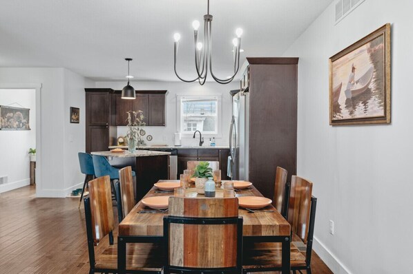 Un comedor moderno con una mesa de madera, sillas y una araña.