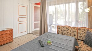 Quarto com uma cama, penteadeira de madeira, mesa com um controle remoto e um pote de vidro, e um sofá.
