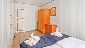 Quarto com cama, guarda-roupa de madeira, penteadeira e espelho na parede.