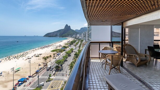 A balcony with wicker furniture overlooking a beach and a mountain. - 802 (Rio de Janeiro)
