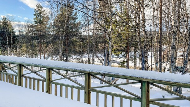 A snow-covered wooden deck with a metal railing, surrounded by trees and a clear sky. - Gorgeous home in os i østerdalen (Os i Østerdalen)