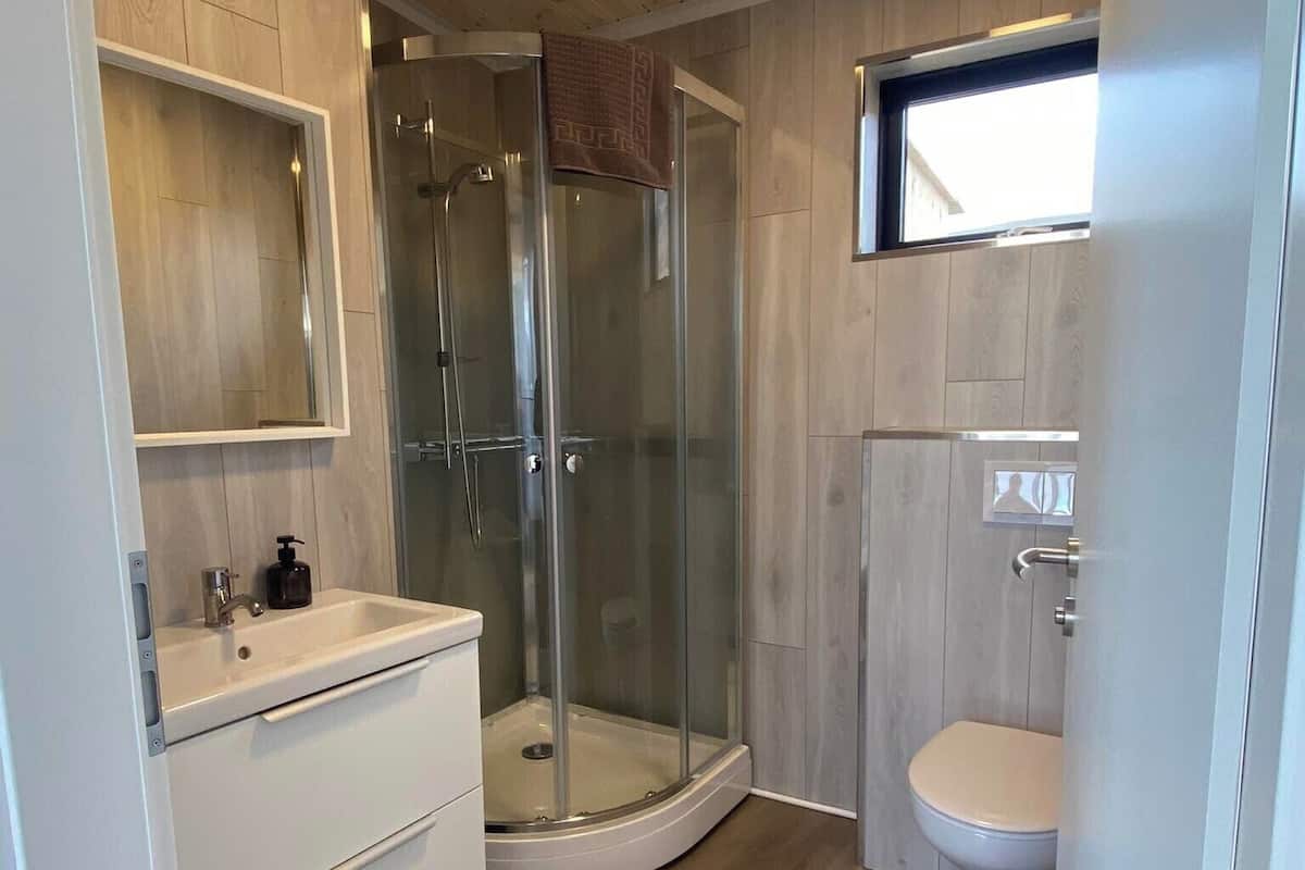 Ett modernt badrum med en dusch som är avskärmad med glasväggar, en vit tvättställ och en toalett.